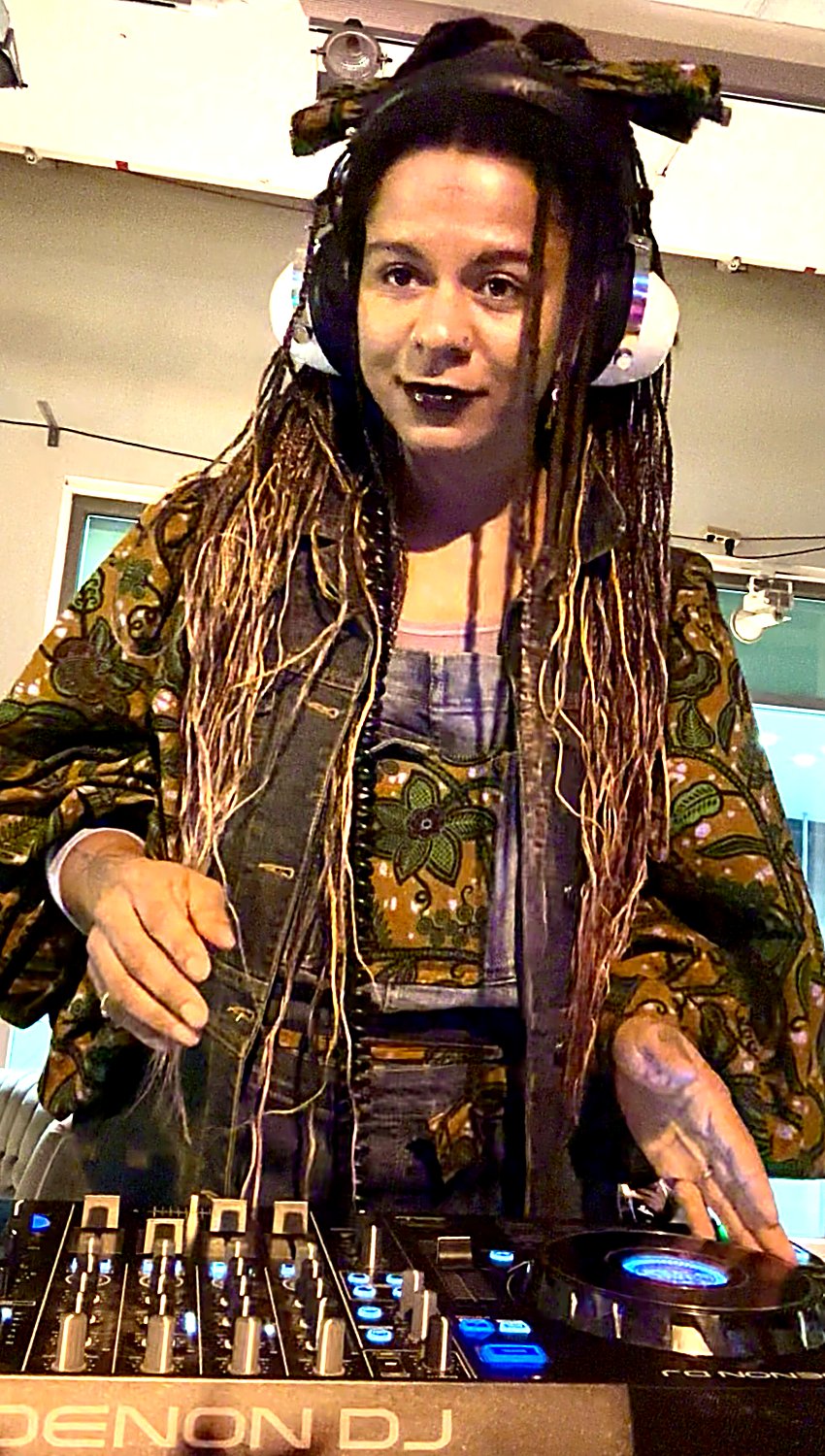 Shida DJing on Denon decks in a patterned wax-print jacket