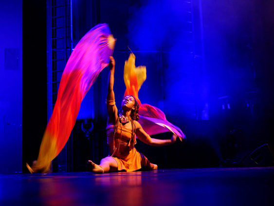 Stage performance with flowing silks under coloured light